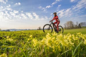 Frau mit E-Bike fährt über ein Feld